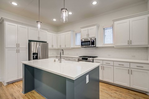 a kitchen with white cabinets and a large center island